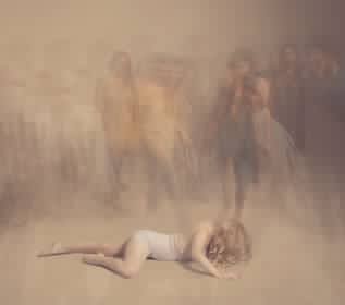 A woman lies on the ground surrounded by figures